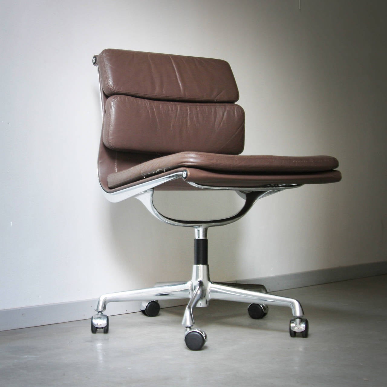 Pair of Eames EA 205 chairs. They are part of the Aluminum Soft Pad Group designed in 1969 by Charles and Ray Eames for Vitra. Brown leather, original no armrests. Can not turn but stand on castors. Beautiful patina, very good condition.