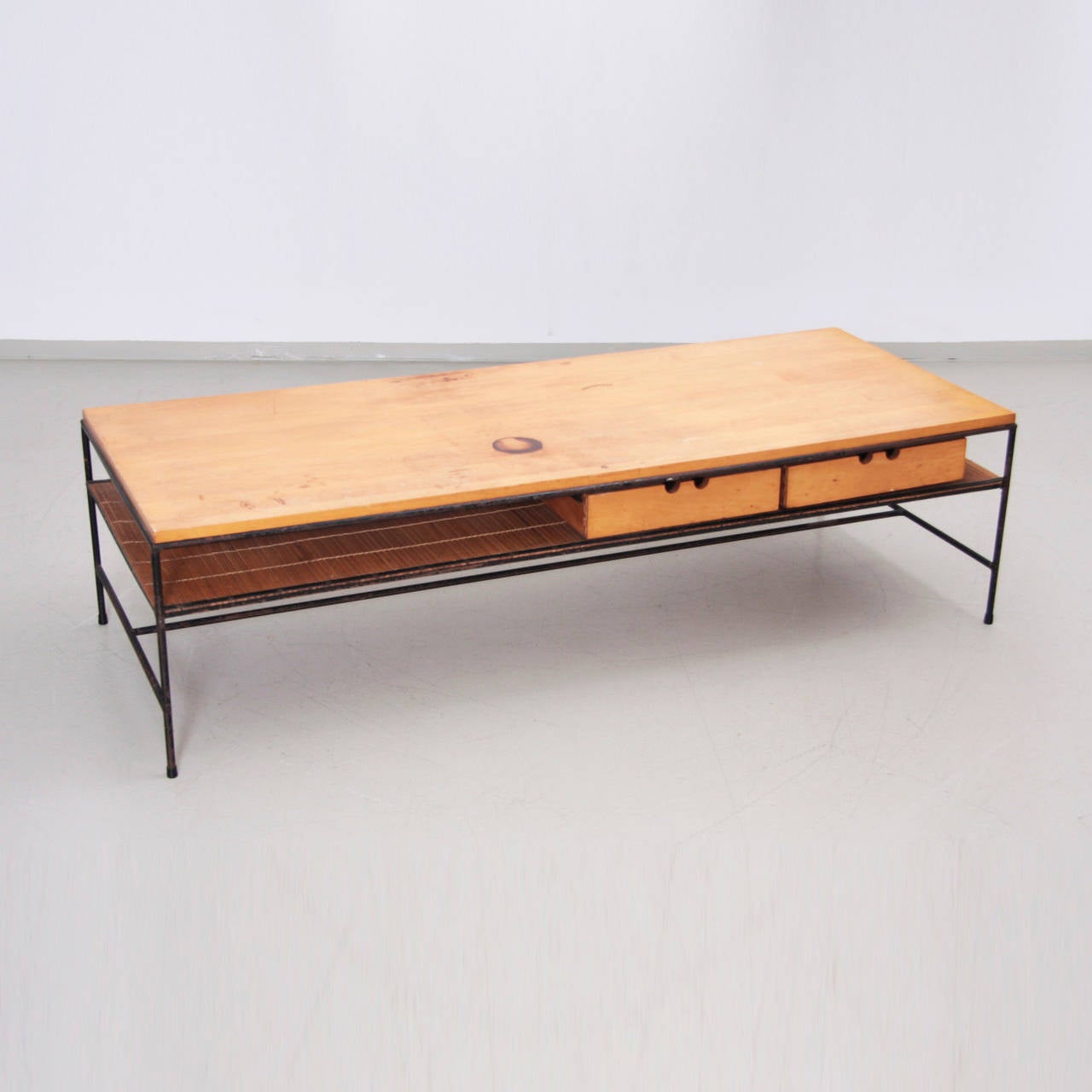 Hard to find early unrestaured version of the work of Paul McCobb Planner Group, for Winchendon Furniture. Vintage condition. Solid maple top, over two drawers and chic bamboo shelf. Wrought Iron frame. Nice big rectangular coffee, cocktail table.