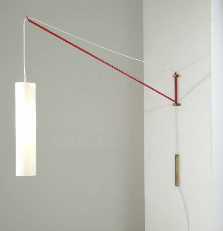 This lamp was designed by mr Mangano, owner of Finform and the Mangano collection. The design is ingeniously simple: a swiveling jib style wall lamp, consisting of a red metal stem, a height-adjustable white cylindric fabric shade (58 cm high) and a