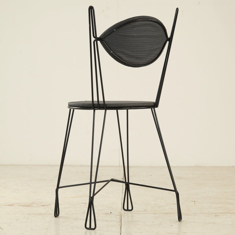 This is an original Ice Cream Parlour group chair made of thin black metal, manufactured by Woodlin Hall.
Although often seen with an open back, the closed upholstered back is a variation that was also manufactured and distributed by Raynor in the