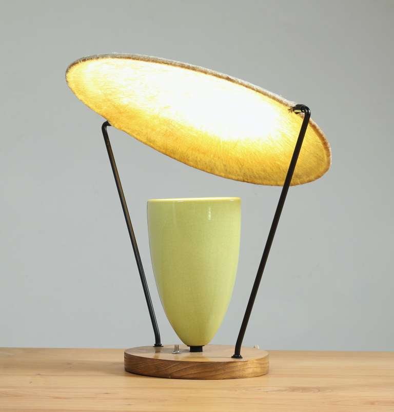 Yellow version of the table top model of Mitchell Bobrick's Control Light lamp.
The shade is adjustable for light refraction and is made of an organic material that reflects the color off the ceramic, giving it this beautiful appearance when lit.