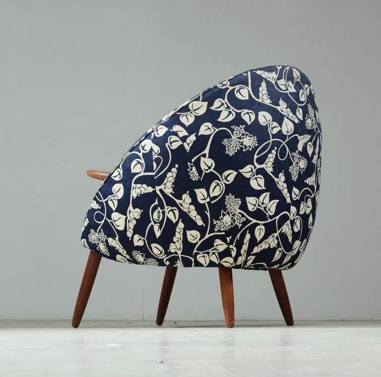 A  beautiful  club chair, attributed to Jørgen & Nanna Ditzel. The chair rests on four slender, tapered legs, has teak arm rests that are integrated into the shell. It is upholstered with blue fabric with a lovely floral motif.
