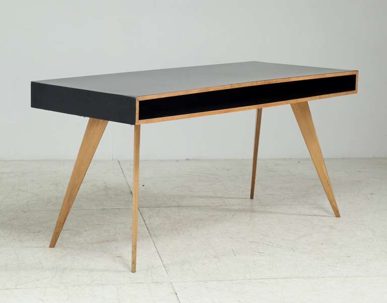 A published 1950s wooden writing desk by Swiss designer Hans Bellman for the German furniture company Domus. The desk stands on four thin, elegant legs and can be used at both sides and has equal internal shelving at both sides.