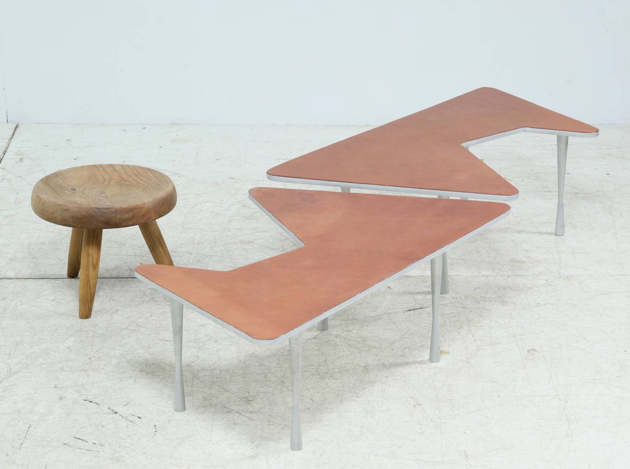 A pair of free-form low coffee tables with a light brown leather top on a aluminium base. Perfect condition.