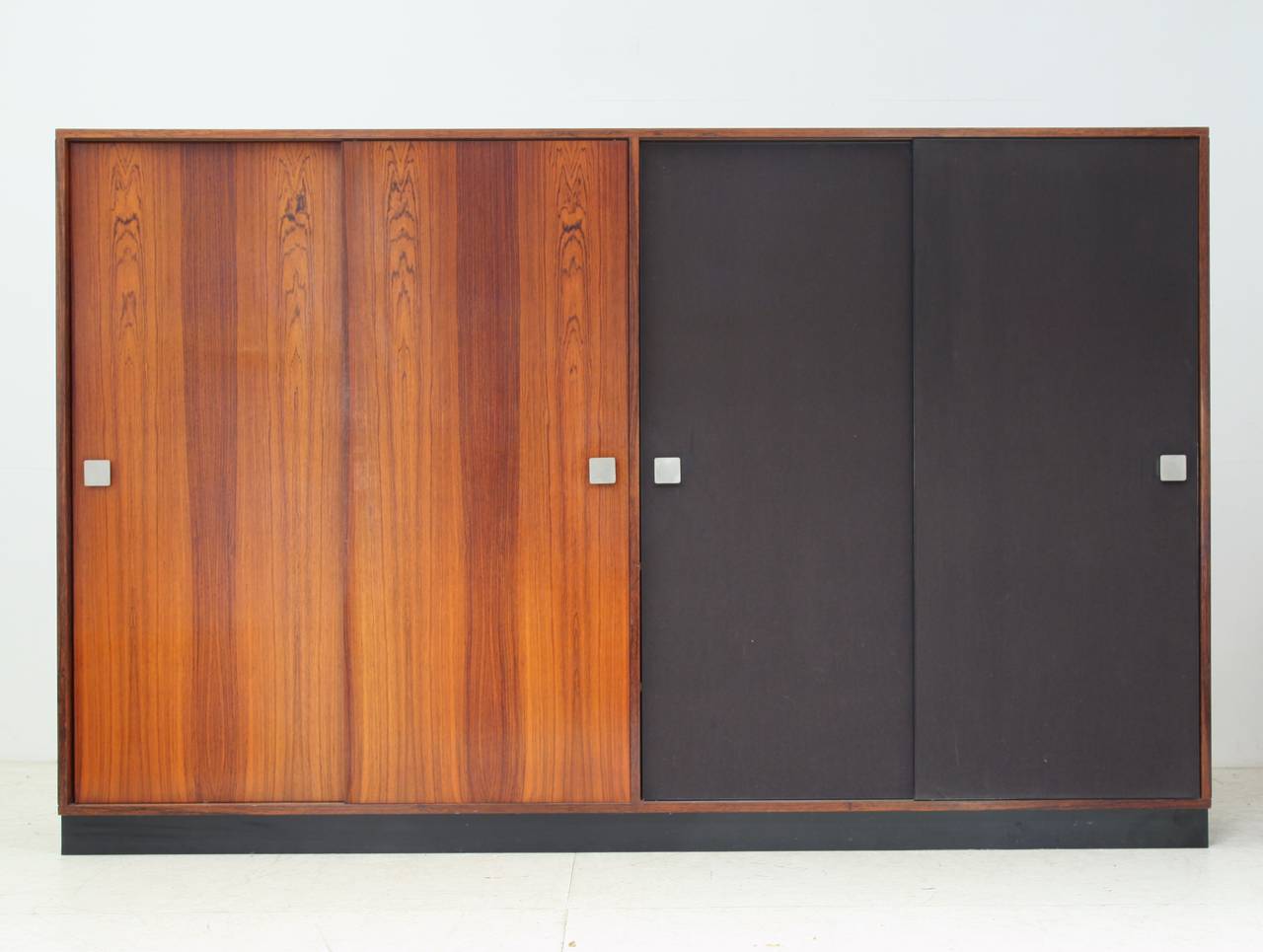 A gorgeous and hard to find large Mid-Century wardrobe by Belgian designer Alfred Hendrickx. It is made of a wonderful rosewood.
The wardrobe holds four sliding doors, one section for hanging clothes and the other section with shelves. 
The doors