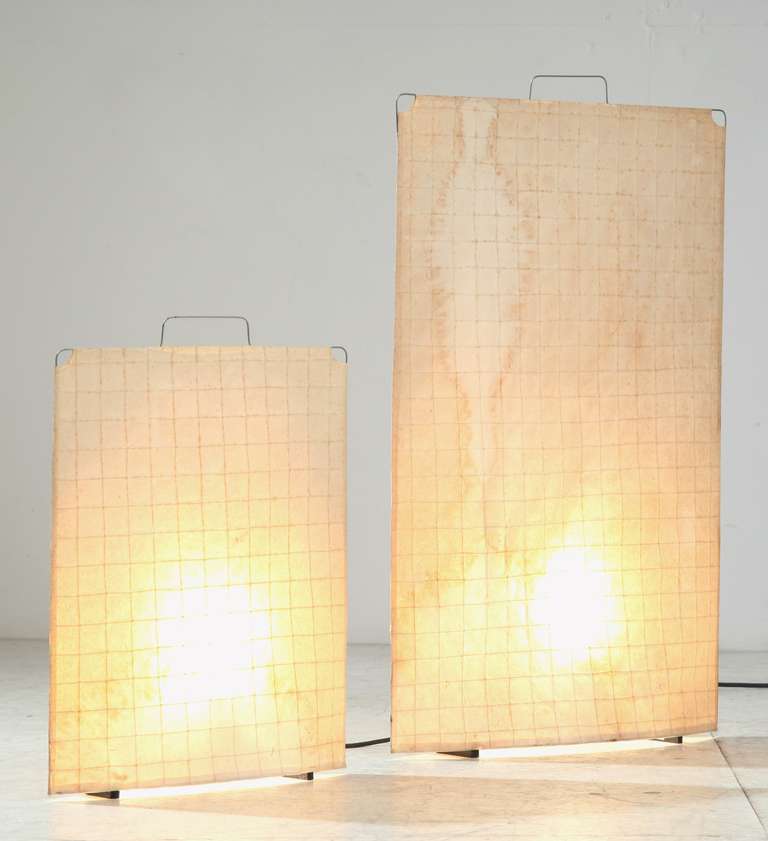 A pair of slim table or floor lamps with a paper shade on a metal frame.

Both have a water stain on one side.