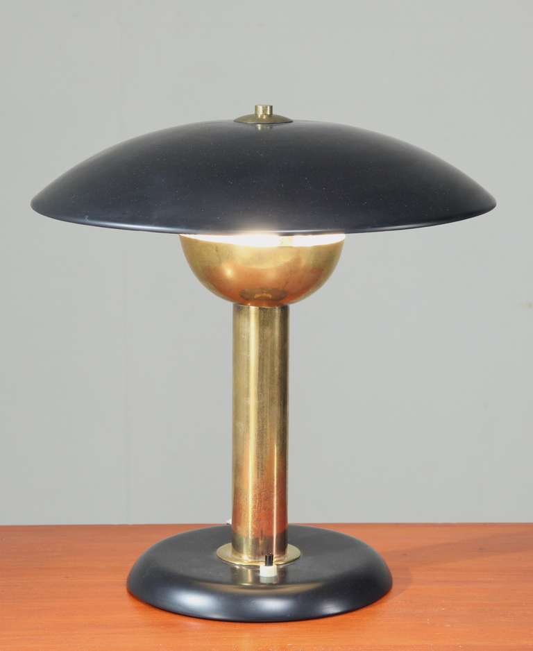 A beautiful, heavy brass table lamp with a black metal foot and shade.
