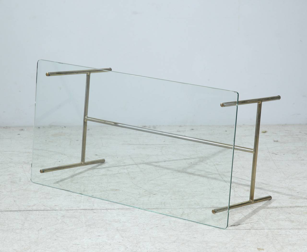 A Pierre Guariche coffee table for Disderot, made of a slim brass frame with a glass top with rounded corners. The glass is fixed with four decorative brass screws. 
This piece is in a perfect and fully original condition.