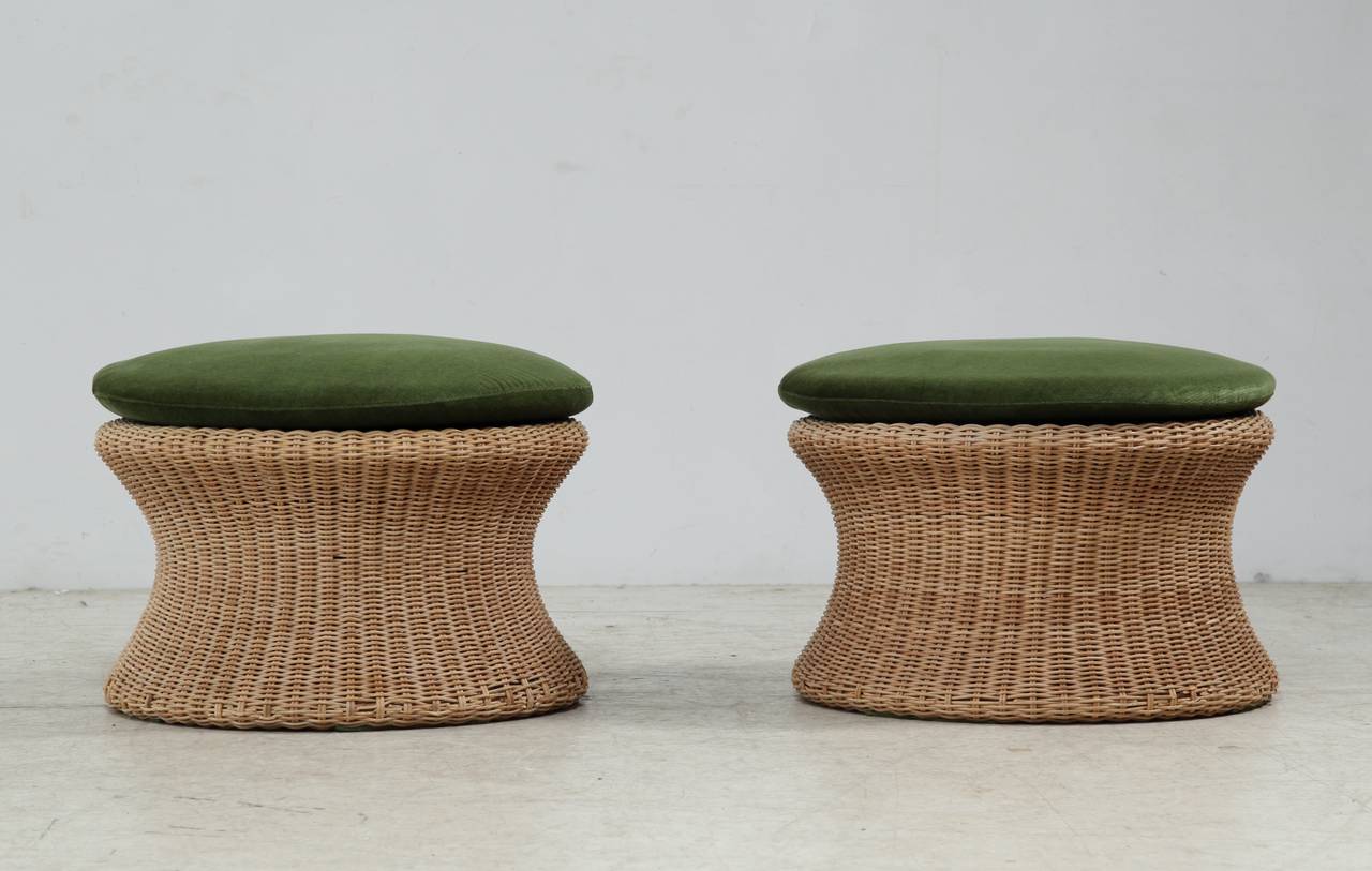 A pair of low Eero Aarnio handmade stools or ottomans in cane. The cane is in a good condition with a great patina. Both stools have the original cushion with a beautiful green upholstery.