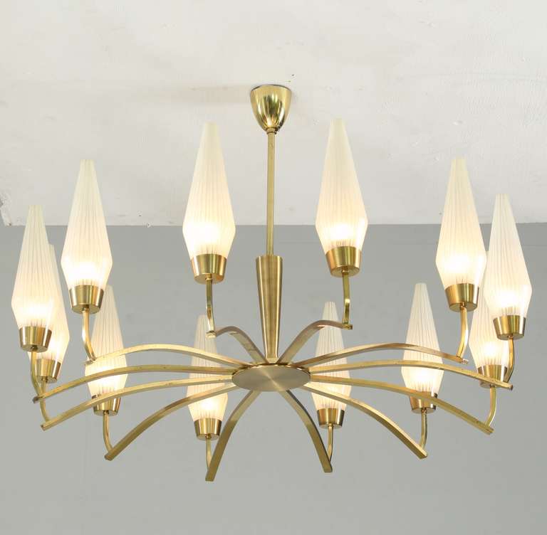 A large brass chandelier with twelve arms, each holding a striped opaline glass shade.