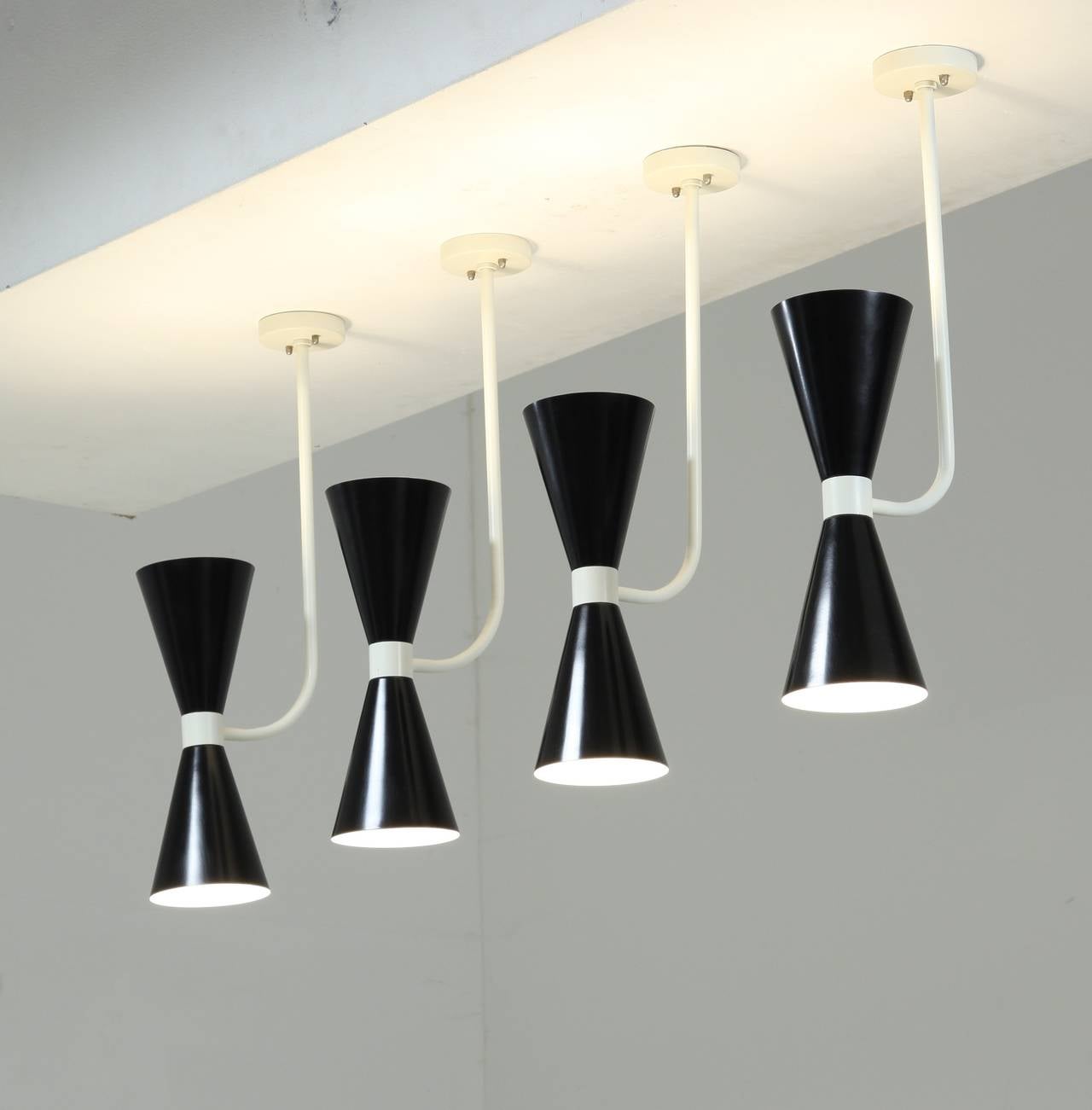 A set of six metal ceiling lamps in the manner of Stilnovo that can be transfered into wall lamps. The lamps are made of a white bent ceiling-mounted stem, holding a black diabolo shaped shade.
We can re-paint the black into any desired color.