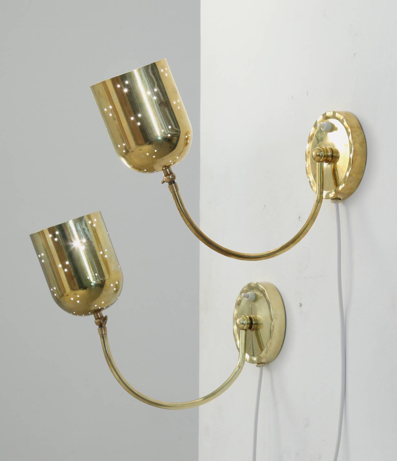 A rare pair of 1950s brass wall lamps by Idman, in the manner of Paavo Tynell. Both have a light switch all the wall mount itself, making it ideal bedside lamps
These fully brass lamps have an adjustable hood, with the pin point perforations we know