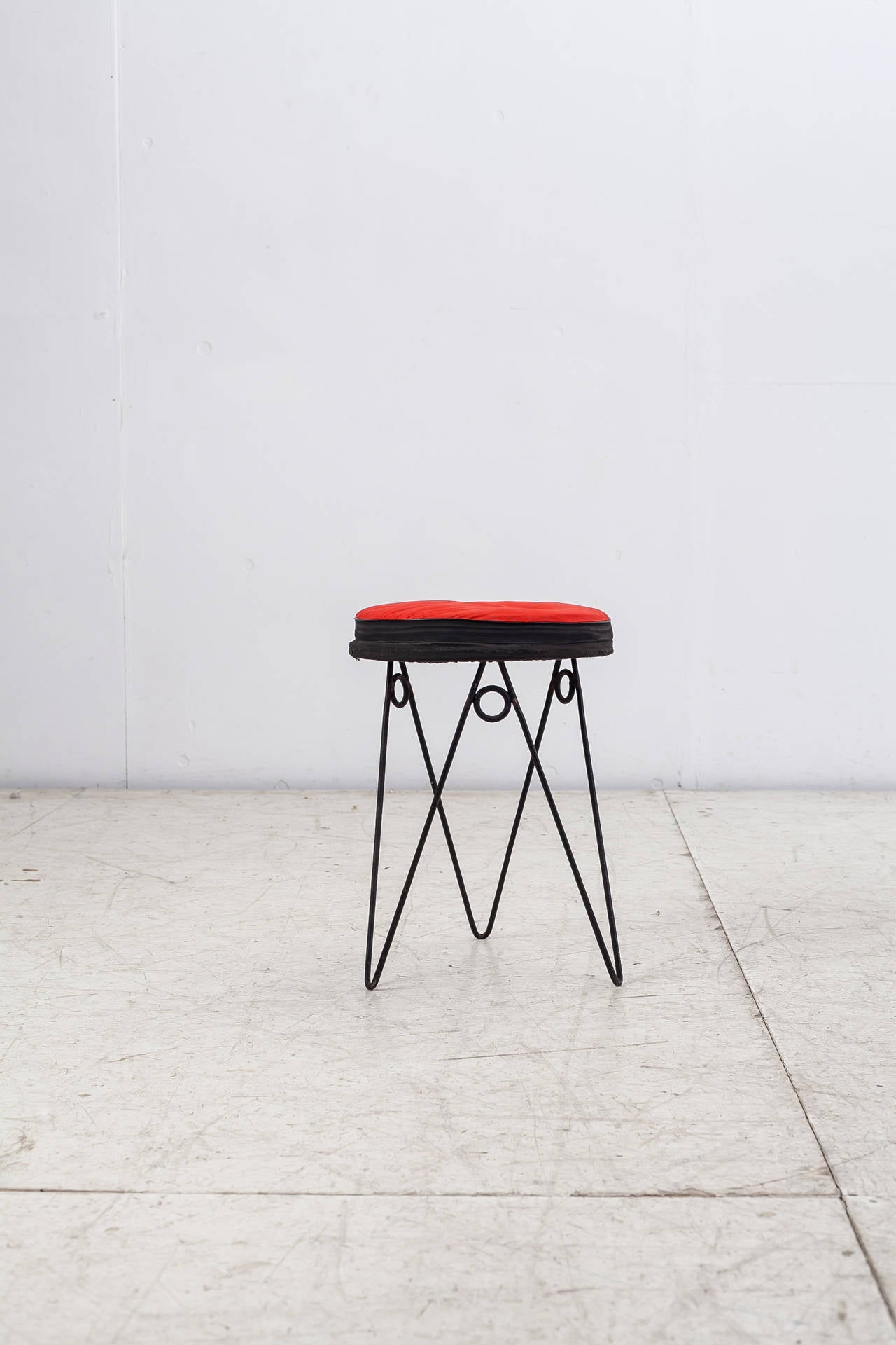 A 1950s French stool by Jean Royère or in the manner of. The stool is made of a playful iron hairpin frame with a black and red fabric seat pad. The frame is strongly reminiscent of Royère's 'Yo-Yo' series.

The seat pad has been professionally