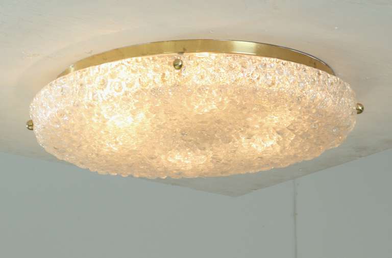 This flush mount has a highly textural bubble surface to the outside. The glass shade is connected with brass screws to the brass ceiling plate, holding six E27 lamp holders. Designed as flush mount and also suitable as wall applique.

* This piece