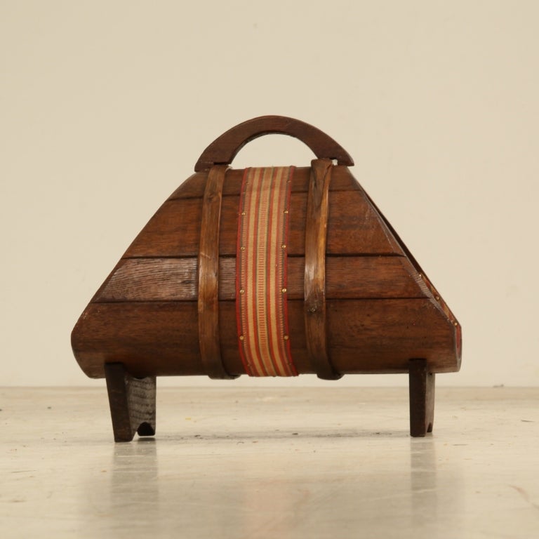 A wooden magazine holder in arts and crafts style with a cloth ribbon around it. Originally used for wine making, now a very decorative piece with beautiful woodwork details, labeled Chianti, Italy. Excellent condition.

