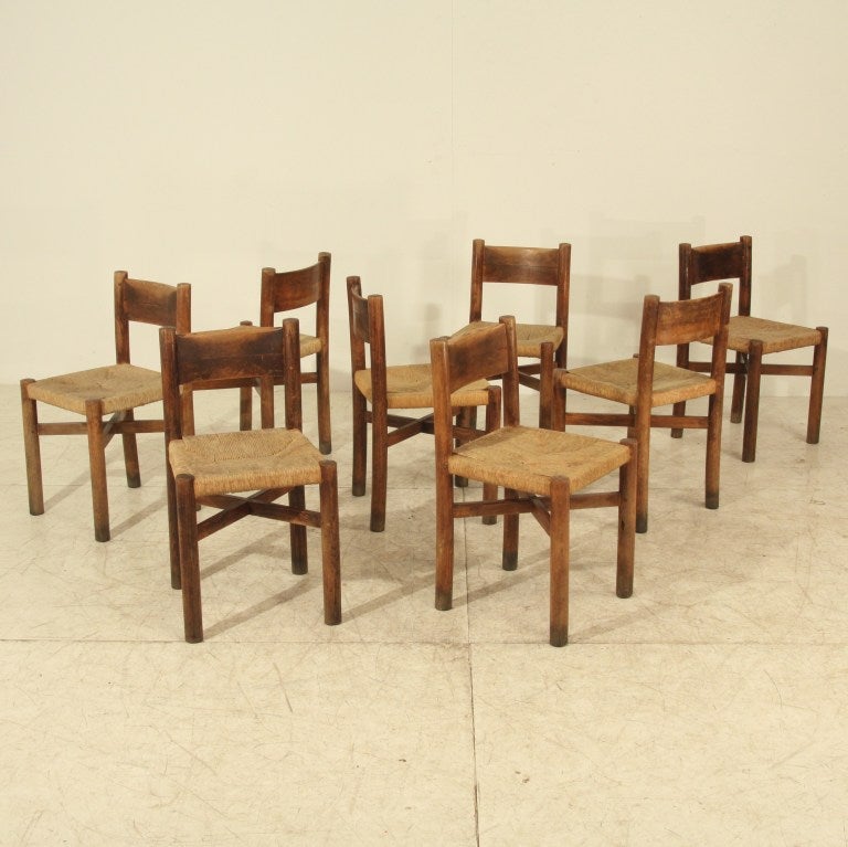 Set of eight beautifully aged Charlotte Perriand 'Courchevel' chairs. Manufactured by Georges Blanchon and designed for the Meribel-les-Allues mountain resort. Oak frame with round supports and curved back rests, with the original rush seats.