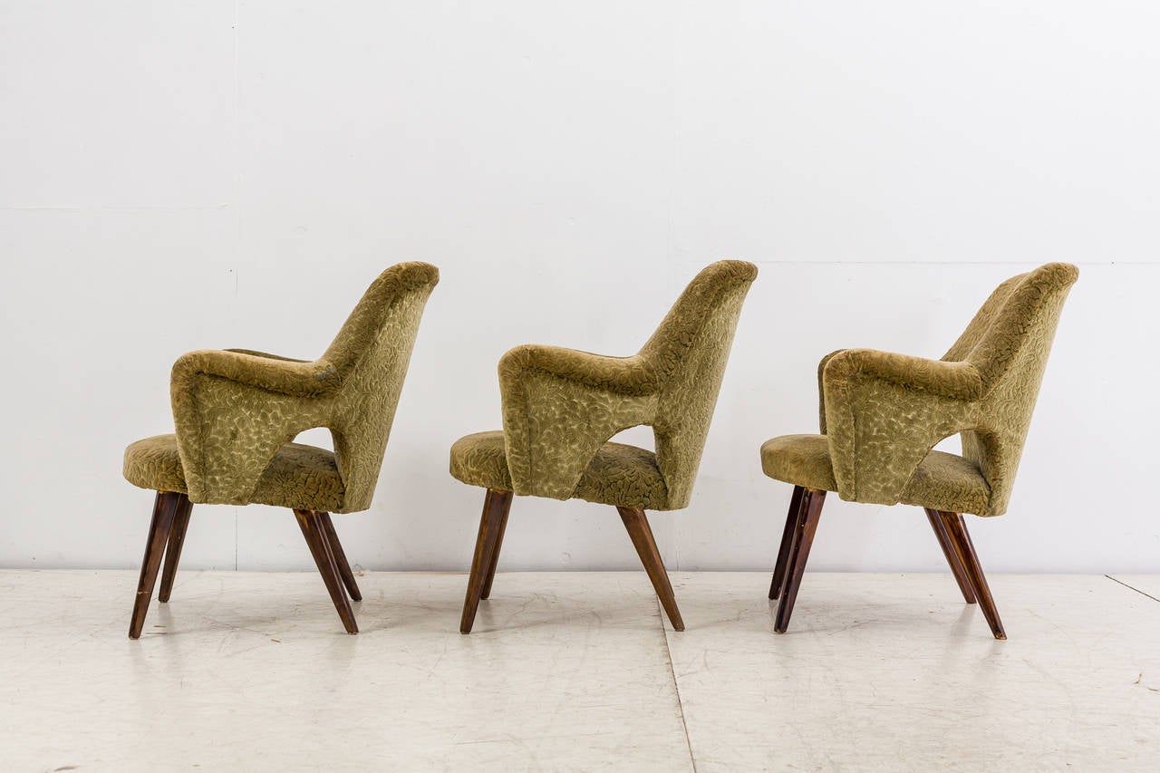 Three lounge chairs with a partly open side, by Finnish designer Carl-Gustav Hiort af Ornas. The chairs are upholstered with a beige-green floral fabric.