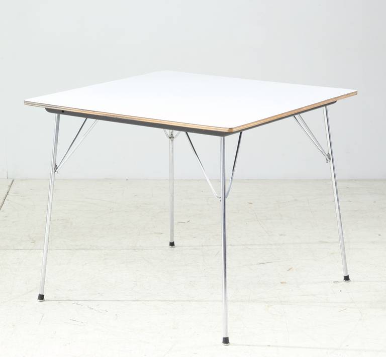 A Charles & Ray Eames DTM table for Herman Miller. The table has a white laminate top and foldable metal legs.
