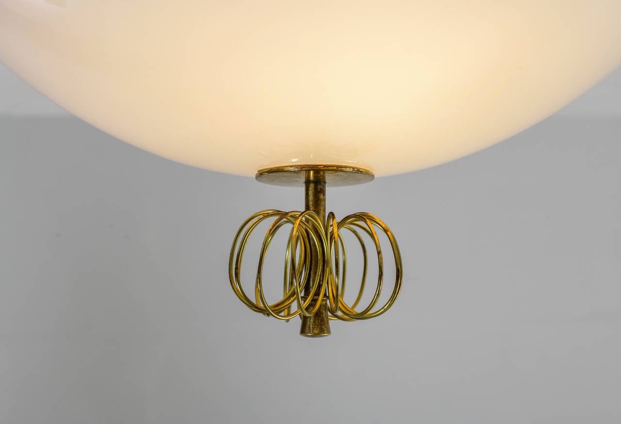 A very rare Paavo Tynell ceiling lamp for Taito, Finland, 1940s.
The lamp is made of a curved and round opaline glass diffuser, with two light bulbs inside. It has a brass ceiling mount and a brass decoration, typical for Tynell's designs.
This