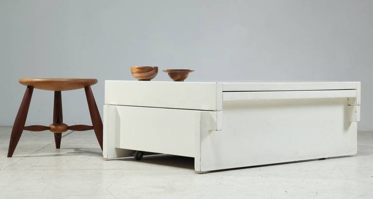 A white lacquered wooden coffee table on wheels by Belgian designers Claire Bataille and Paul Ibens, in the manner of their work for t Spectrum. The top can slide open to give access to a small bar.