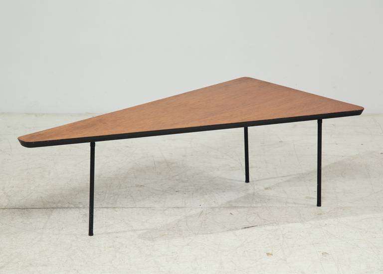 A rare American coffee table from the early 1950s. The triangle-shaped wooden top rests on a metal base with three legs.