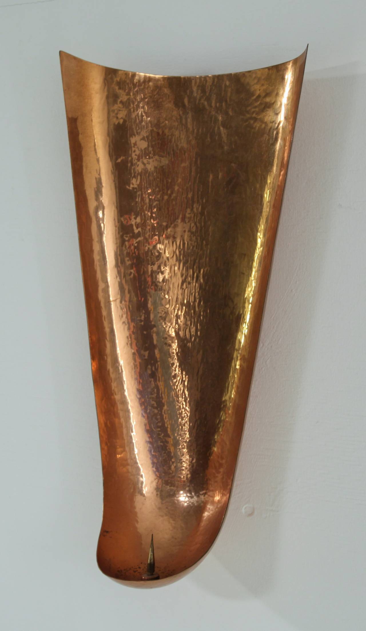 A superb candleholder made of hand-hammered copper. The large concave holder gives a beautiful light reflection and can be mounted to the wall very easily.
