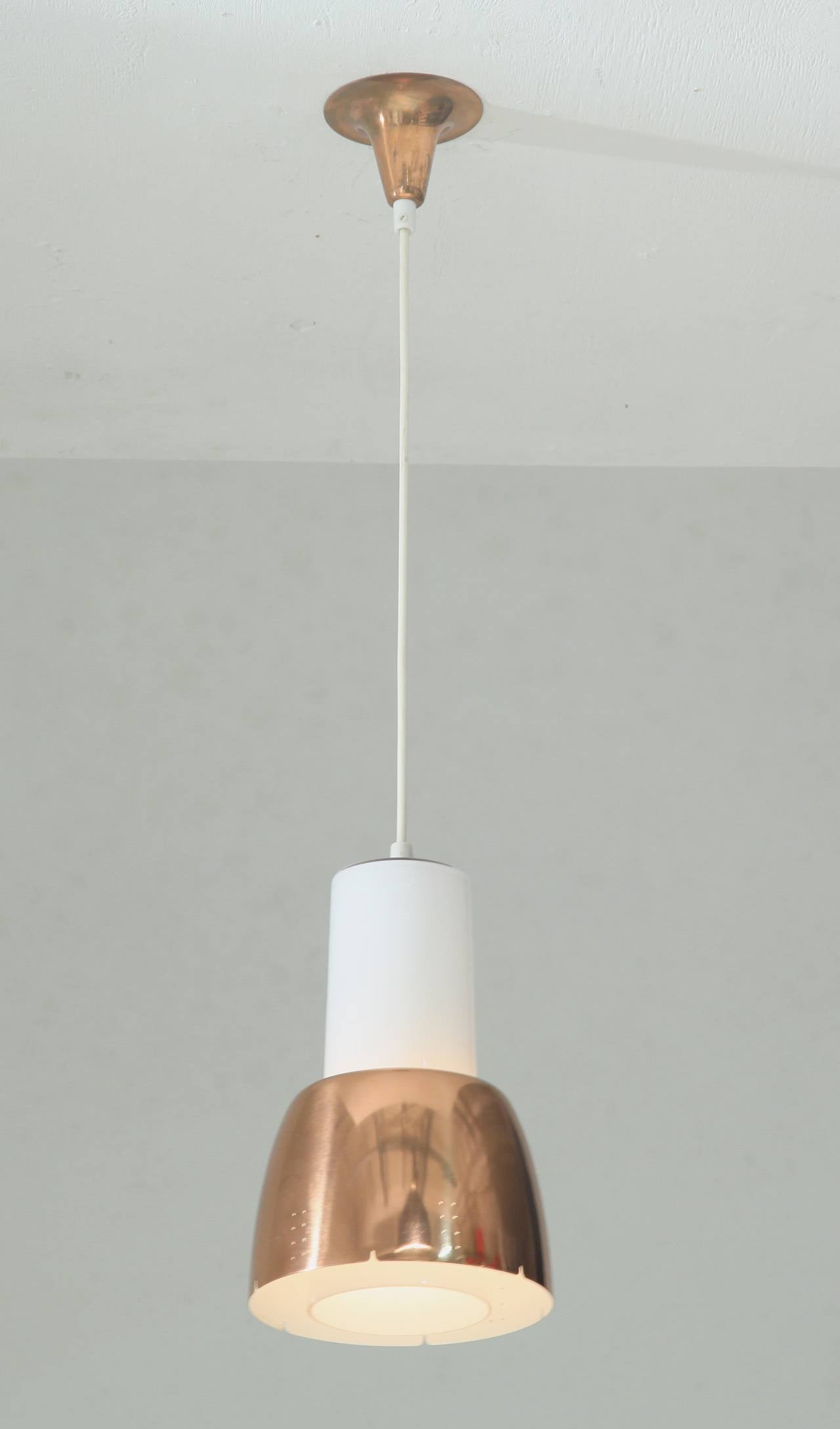 A model K2-16 pendant lamp by Paavo Tynell for Idman. The lamp has an opaline glass cylinder diffuser with an elegant copper shade with twin dot perforations.
The lamp is marked by Idman and in a perfect condition.