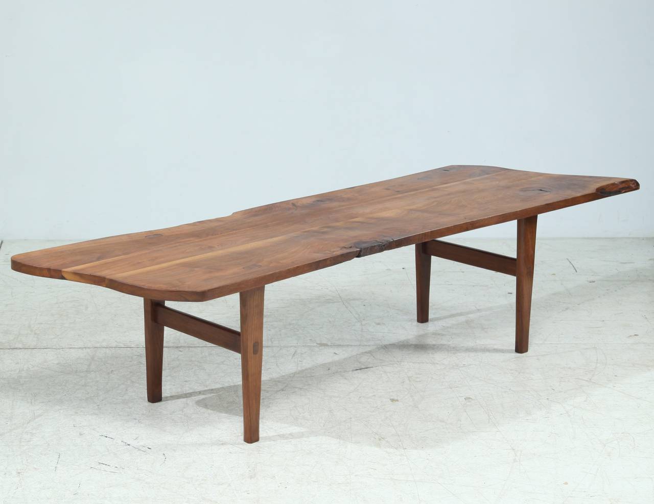 A spectacular handmade walnut bench made by an American woodworker. The wood has a warm color and has aged beautifully. The rough texture of the top contrasts nicely with the more smooth legs.