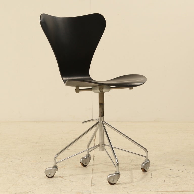 Early Arne Jacobsen height adjustable desk chair on wheels. Denmark, 1950s. With label and in a perfect condition. 
Seat height is adjustable from 45 to 49 cm and the height will vary accordingly from 76 to 90 cm.