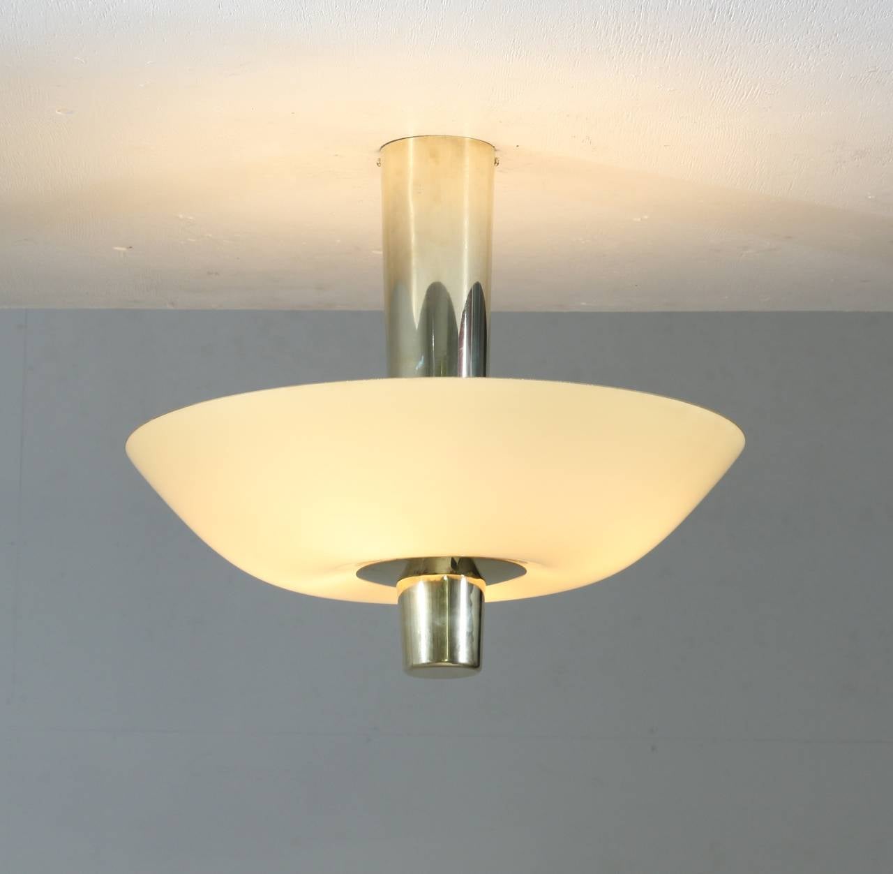 A Paavo Tynell model 9053 ceiling lamp for Idman with a long brass cylindrical stem holding four lamps inside the light yellow shade.
The chandelier is in perfect condition and matches very well with the other 9053 Tynell flush mount in our