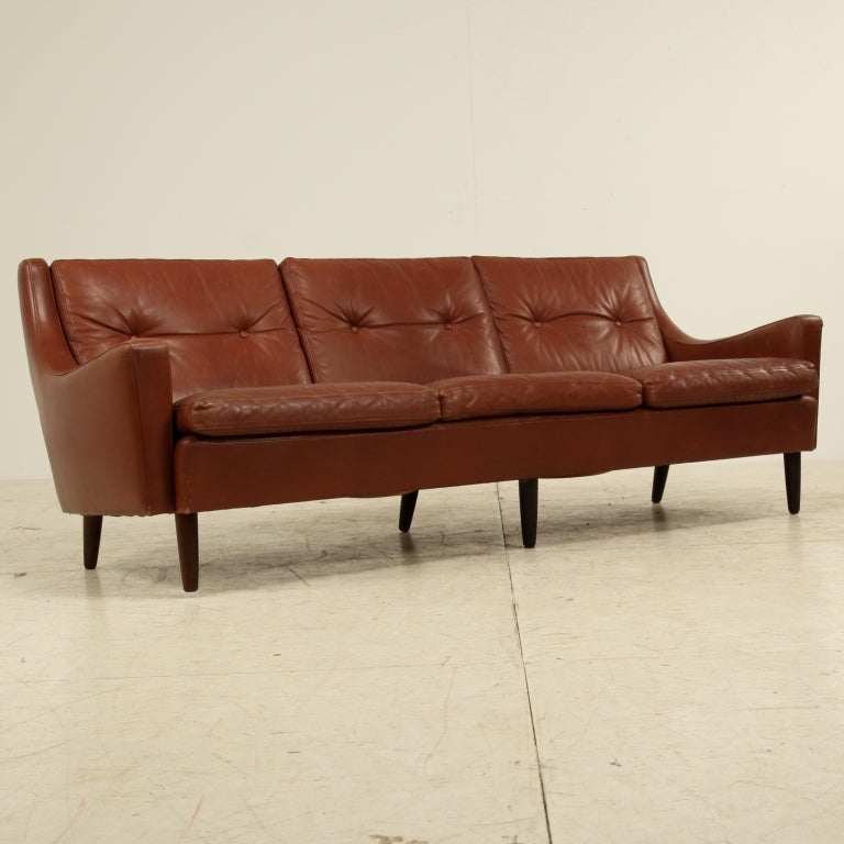 A brown leather Danish three-seater sofa in the classic manner of Borge Mogensen. The buttoned back cushions, rounded edges of the armrests and the tapering wooden legs give an elegant touch to this Scandinavian sofa. Excellent condition.