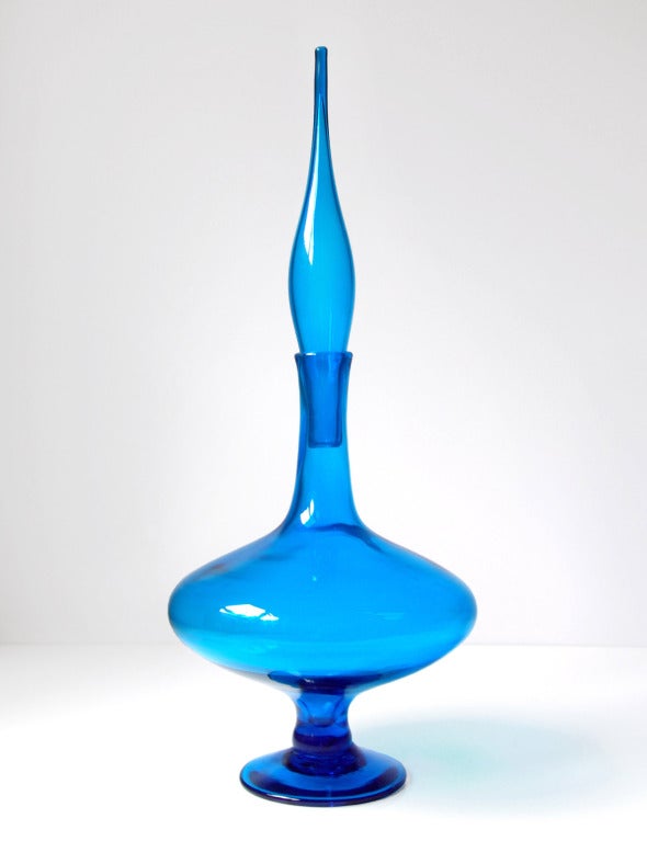Extremely large and elegant footed genie decanter with wide oblong body, tall neck & thin flame stopper, designed by Wayne Husted in 1962.
Design #6212L in Turquoise, pictured in the 1962 catalog.