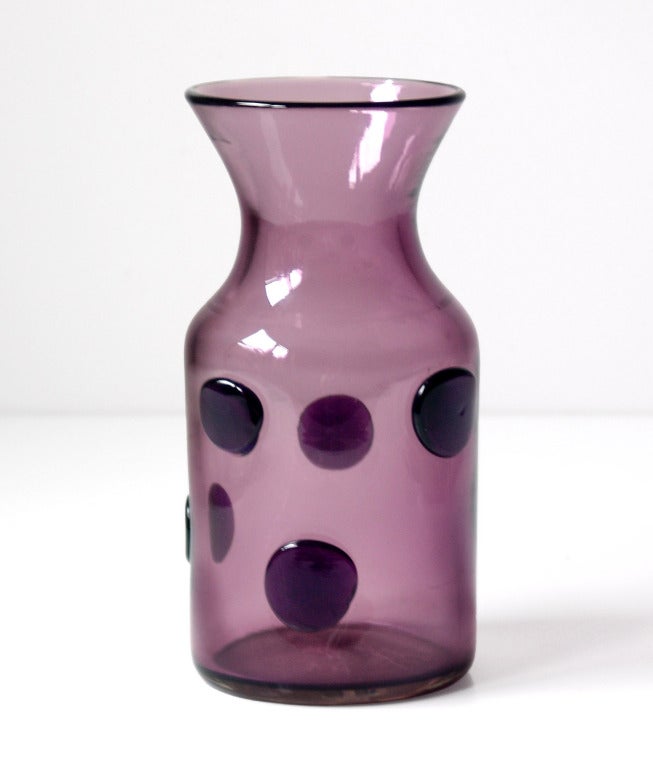Cylindrical vase with flared opening and five applied glass disks, designed by Wayne Husted in 1959, made for 2 years only.
Design #595 in Lilac, pictured in the 1959 catalog on the thirteenth color plate