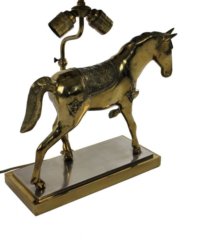 A French gilt bronze table lamp in the form of a horse by Maison Jansen. Of good weight and quality and with its original faux cork shade.