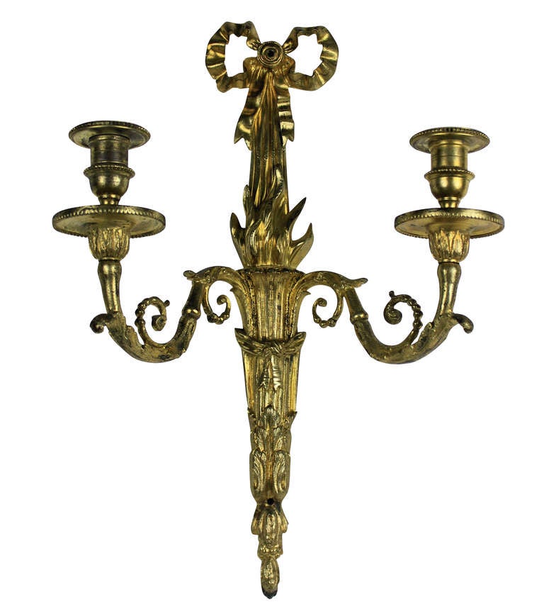 A pair of French, gilt bronze, twin branch wall lights depicting ribbons and a flambe.