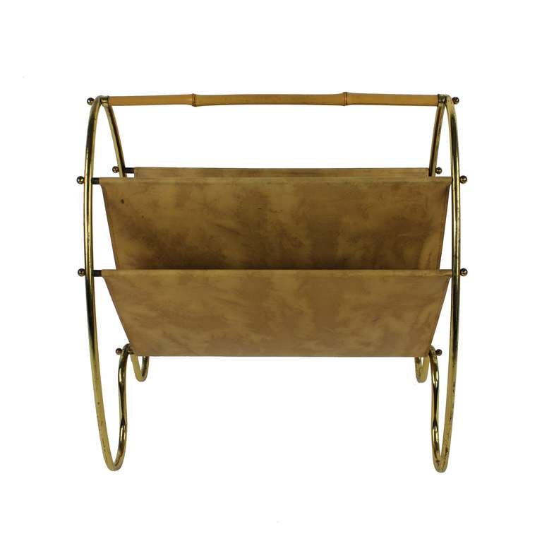 A French magazine rack of elegant design in brass with a cane handle and leather holder.
