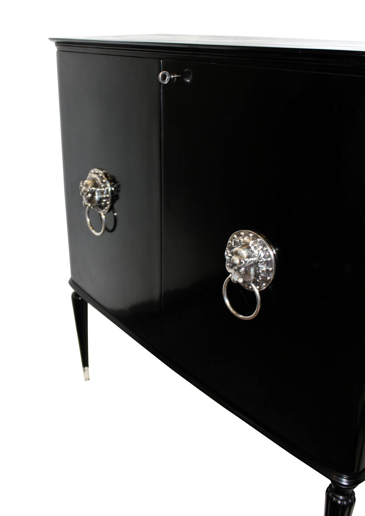 An Italian black lacquered bar cabinet of unusual design. Comprising a fitted interior with drawers and shelves, fine tapering fluted legs with silver sabot and each door has a silver Oriental mask feature.