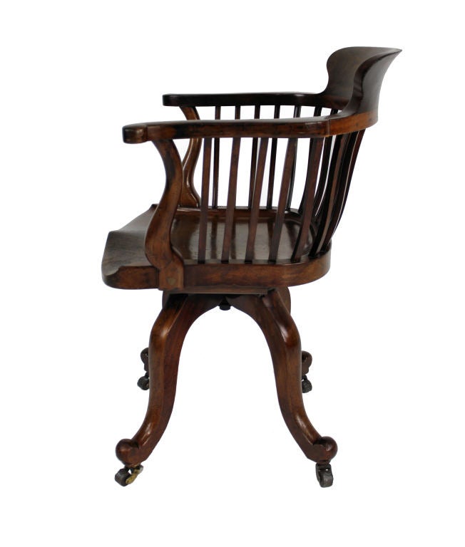 An English desk chair of fine quality by Edward Godwin for James Peddle. In walnut with a sturdy iron swivel mechanism.