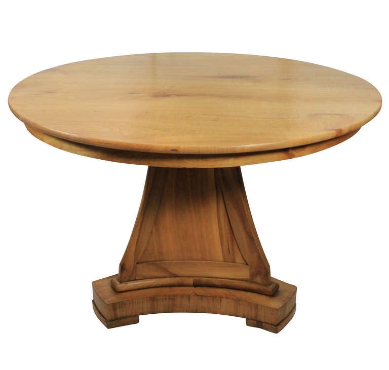 A German Biedermeier table of good design in pale cherry wood. The triform base is interesting in that the panels are concave.
