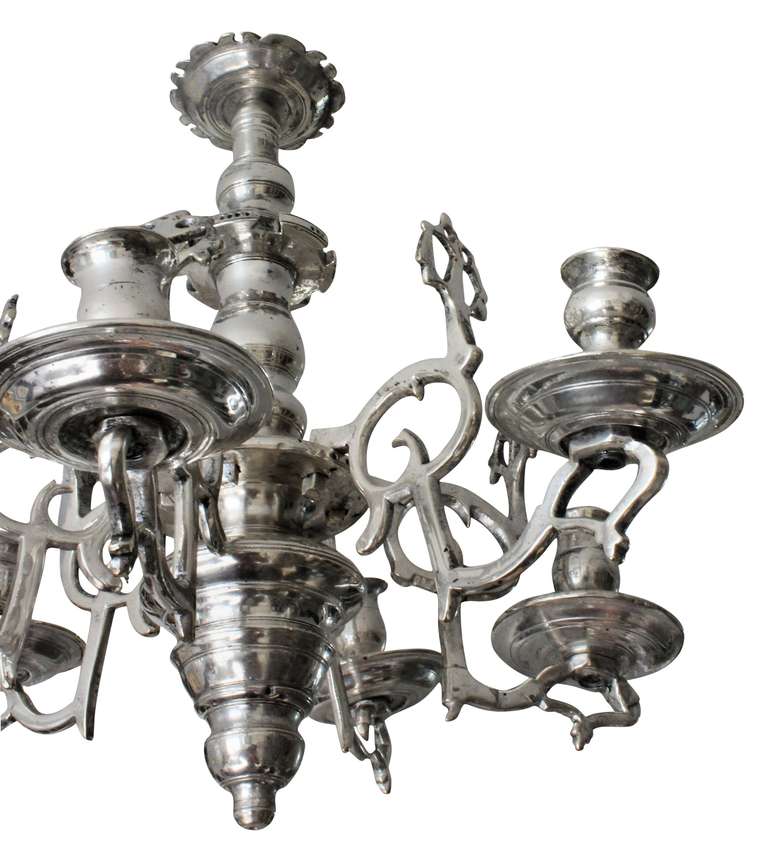 A Flemish chandelier of early design in silver plated brass. of bulbous form with drop in arms, large drip sconces and florid light reflectors.