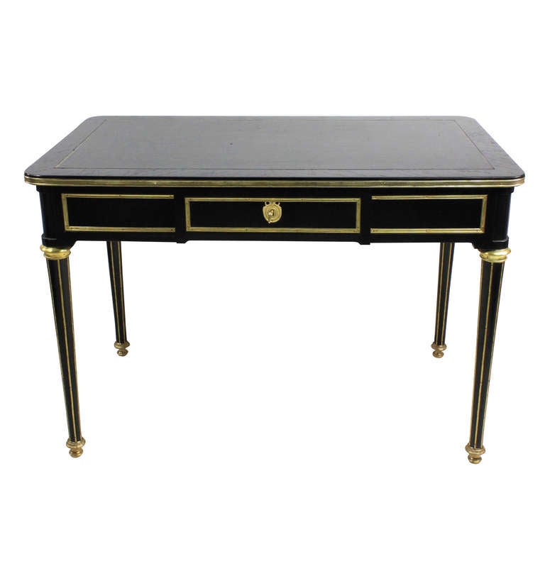 A French desk in the Directoire style by Maison Jansen, Paris. Of good quality of ebonised mahogany, with brass inlay. It comprises a central lockable frieze drawer with two side drawers and a black leather top. Signed Locks.