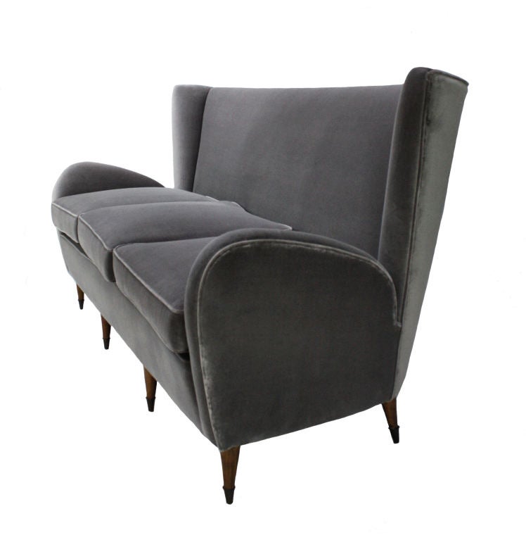 An Italian settee by the Milanese architect Paolo Buffa. Designed for the Hotel Bristol in Merano. Retaining the original sprung seats and pads and en suite with a pair of armchairs. Newly upholstered in grey velvet and on tapering cherry wood feet
