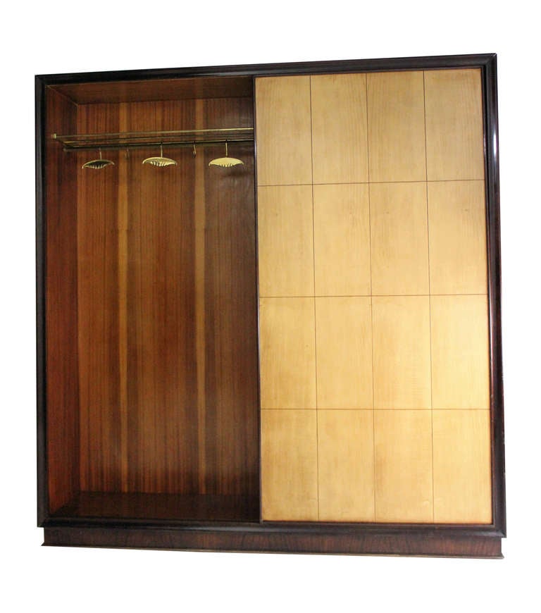 An Italian coat cupboard of large proportions in rosewood and lemonwood. Comprising two sections with a sliding door, one for storing coats.