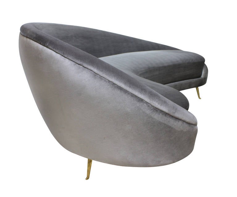 An Italian curved asymmetrical sofa in the style of Ico Parisi, possibly manufactured by I.S.A. Bergamo, circa 1955, on brass feet and newly upholstered in silver-grey velvet.