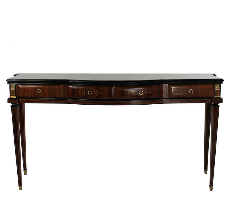 An elegant console table of large proportions by Paolo Buffa, Milan. In rosewood, ebony and with birch lined drawers, brass mounts and a beige glass top. With four sculptured drawers and long slender tapering legs, it is in the Neo Classical
