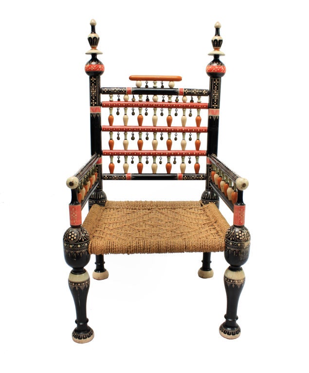 A pair of heavily decorated Indian armchairs from the Pujab. In ebony, faux ivory and decorated throughout with bells. These rush seat chairs would have been used for special occasions such as Weddings.
