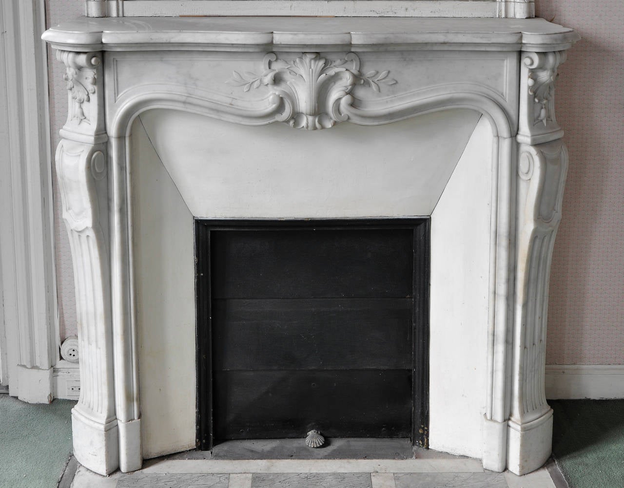 This antique Louis XV style fireplace was made out of white Carrara marble in the 19th century. 
This fireplace comes with its original enameled insert but without marble floor.