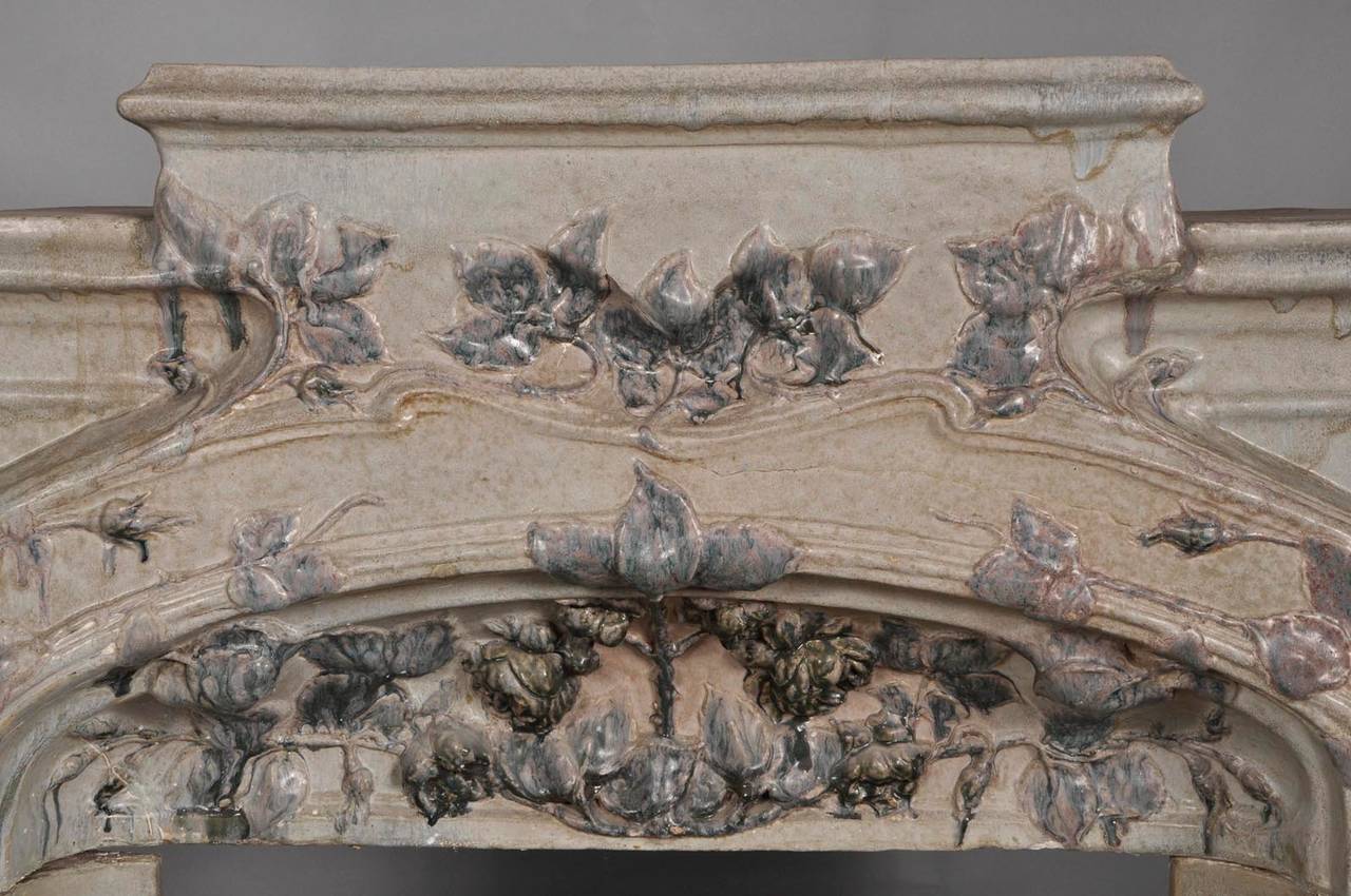 This rare Art Nouveau fireplace was made out of stoneware, circa 1900. The décor of foliages and flowers is in relief and dark blue color which contrasts with the pale blue of the background.