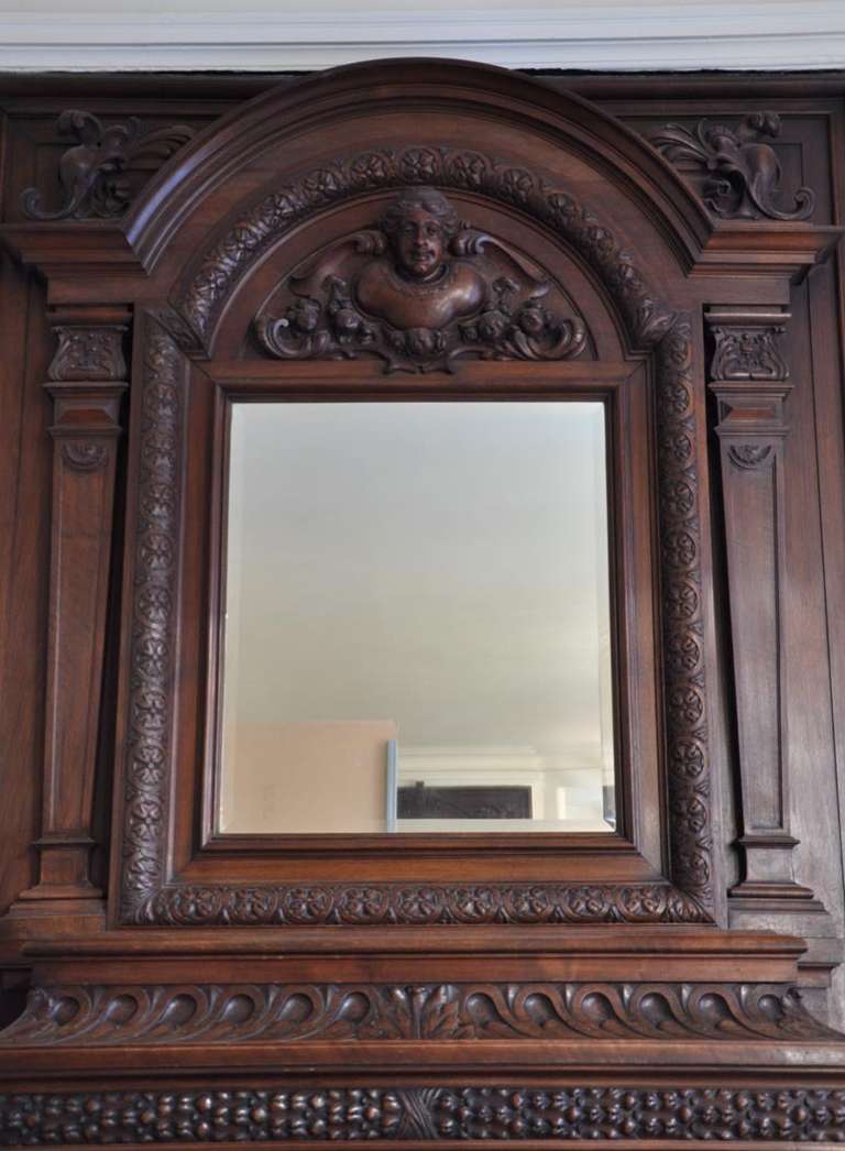 Napoleon III style, this fireplace is completely carved over its entire surface. Thus, the upper part of the mantel is formed by a large pierglass, framed by two fluted pilasters. It's crowned by an arch, ornated with a putti head. 
Both legs of