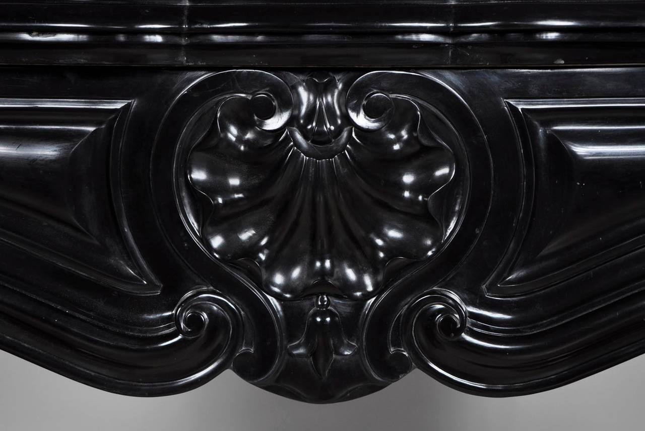 Small dimensions for this antique Louis XV style fireplace in fine black from Belgium marble during the 19th century. This fireplace is carved with three shells on the frieze. 
The Belgian black marble is the only plain black marble in the world.